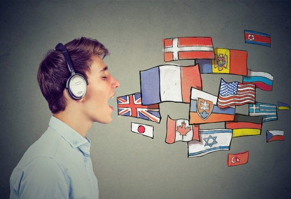 Man listening to music on headphone, the idea of a polyglot is given through the many flag drawings that are as if coming from he man's mouth