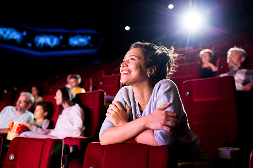 Man sitted in front of a Television with many movie posters next to each other in the screen