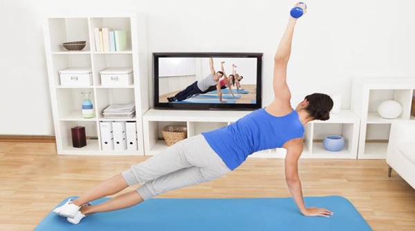 Woman doing a workout exercise at home by watching a workout tutorial on a television